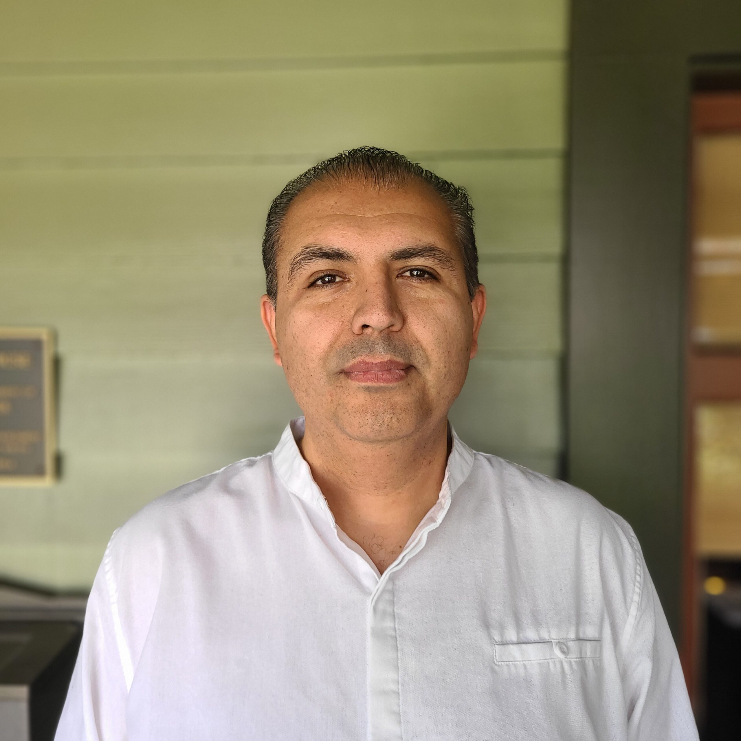 Headshot of Carlos Zuniga against Institute for Educational Advancement's green house exterior