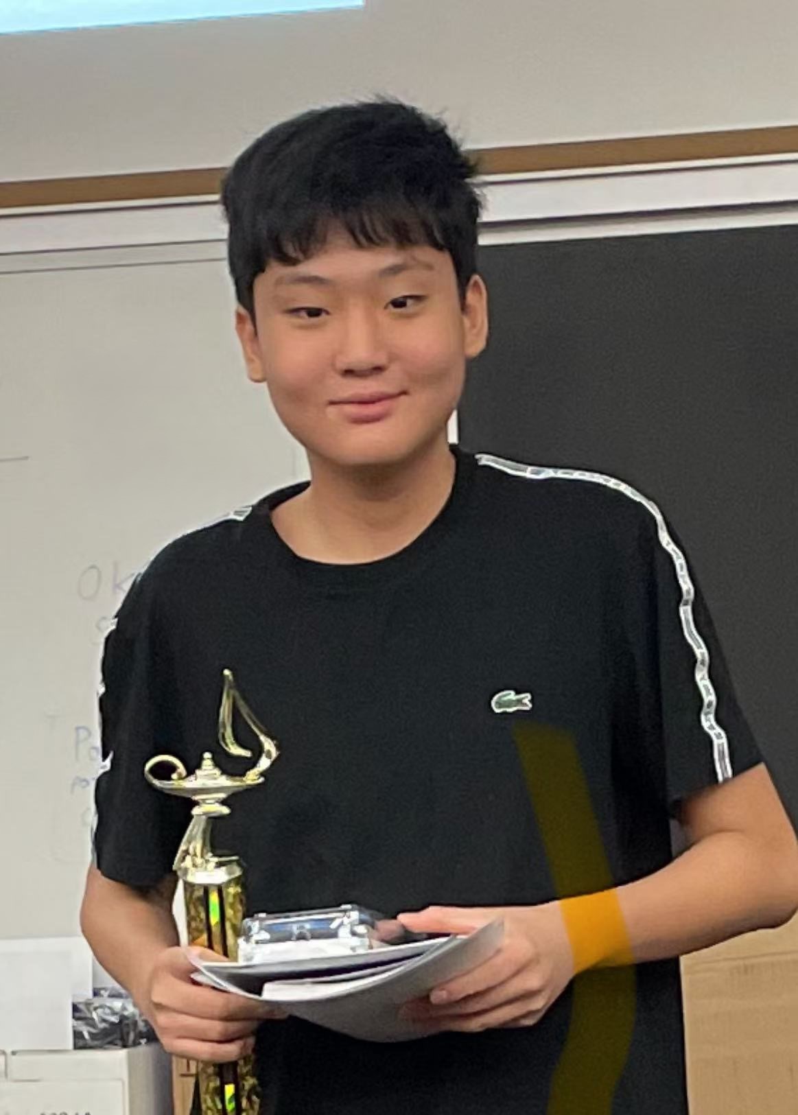 Channing Yang smiling in a Black T-Shirt holding a gold-colored trophy