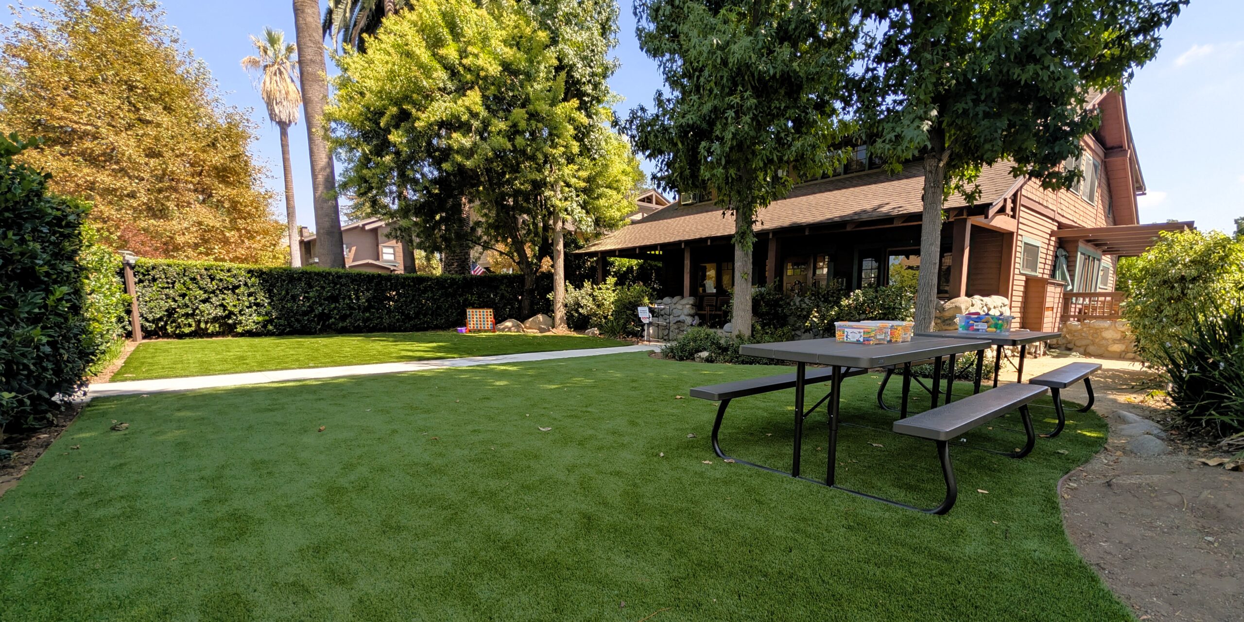 large green lawn with picnic tables in front of a historic craftsman that houses IEA's Learning Center