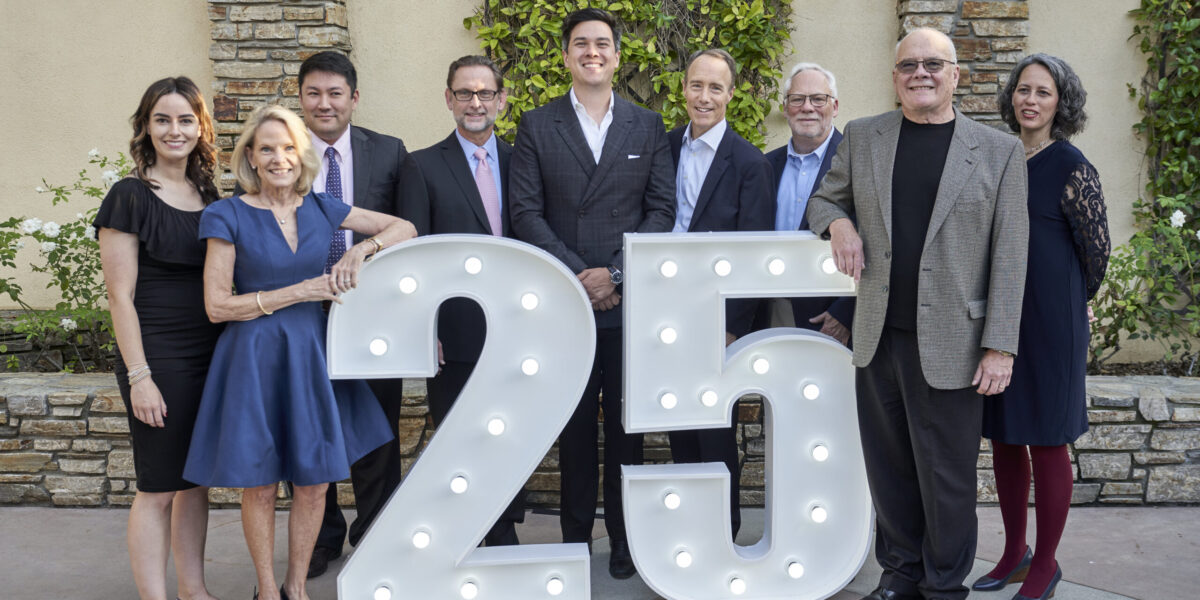 IEA Board of Directors standing behind a 25 marquee light sign at the 25th Anniversary Celebration Gala