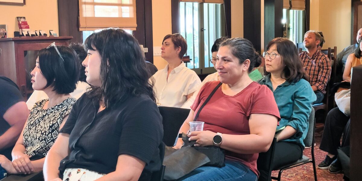 Parents sitting in rows in a living area, smiling during a presentation
